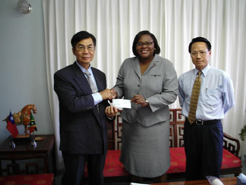 Resident Ambassador of the Republic of China on Taiwan, His Excellency John K. Liu (l) presents monetary contribution to Acting CEO of the St. Kitts Tourism Authority, Ms. Christine Walwyn, while Counselor, Mr. Franklin Chen looks on.